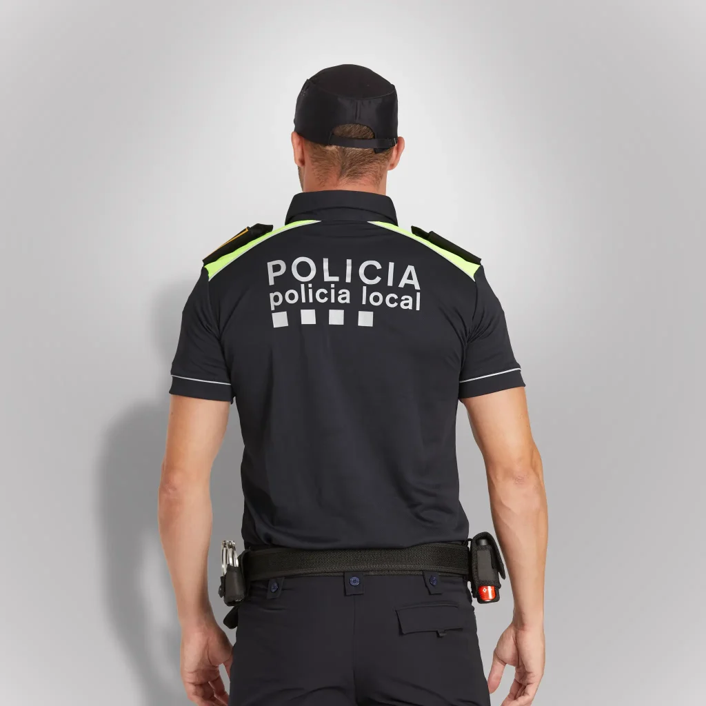 Agente de policía de espaldas vistiendo polo camisero técnico de manga corta azul noche con hombros en amarillo flúor de Cataluña | Serie Origen | Satara